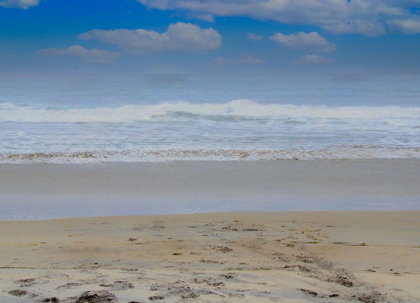 Waves roll onto Rosarito Beach as palm trees line the bright shoreline under clear skies. - Ensenada, Mexico 