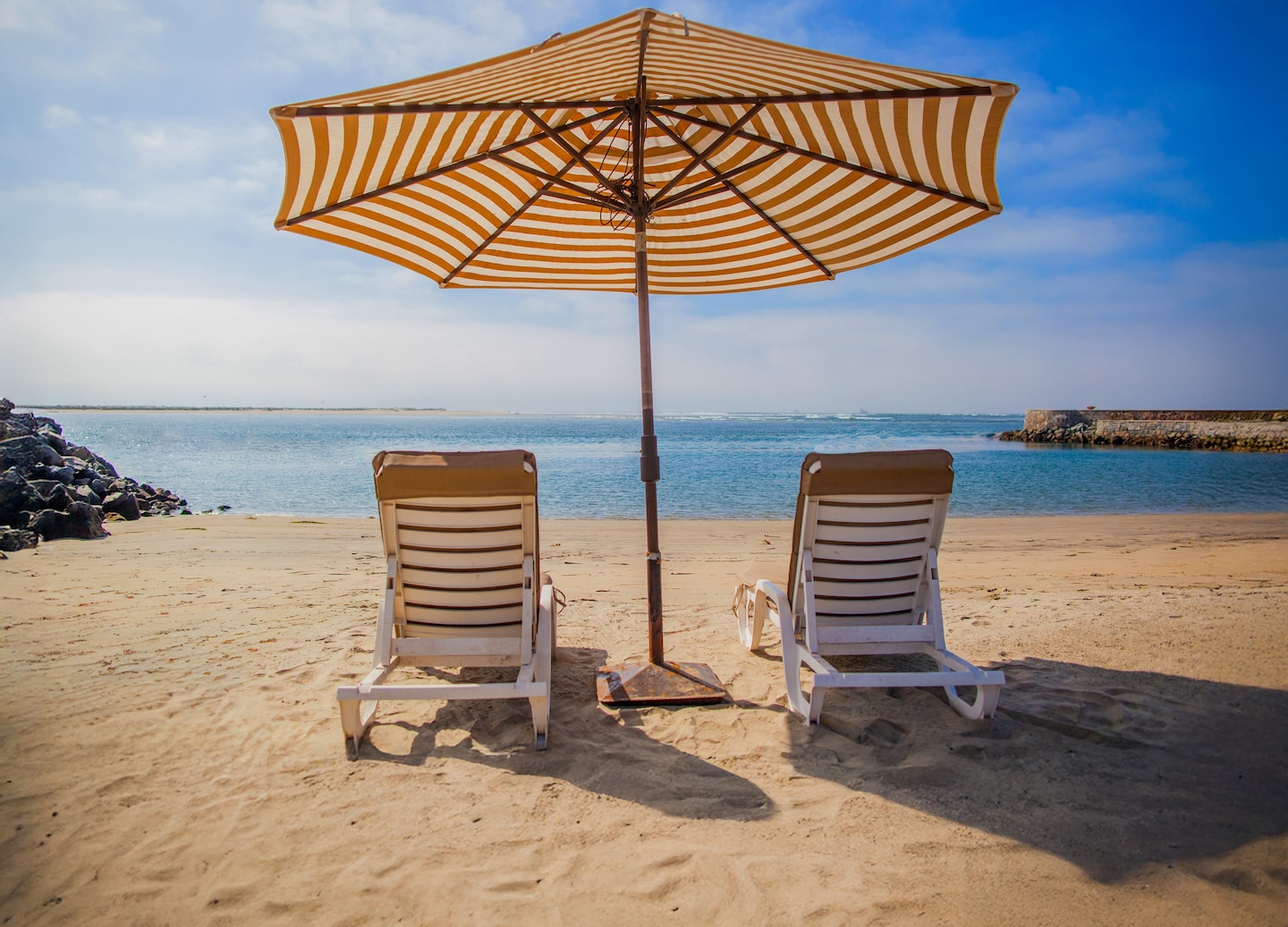 A couple enjoys a tequila tasting beside Estero Beach, with calm blue water in the background. - Ensenada, Mexico 