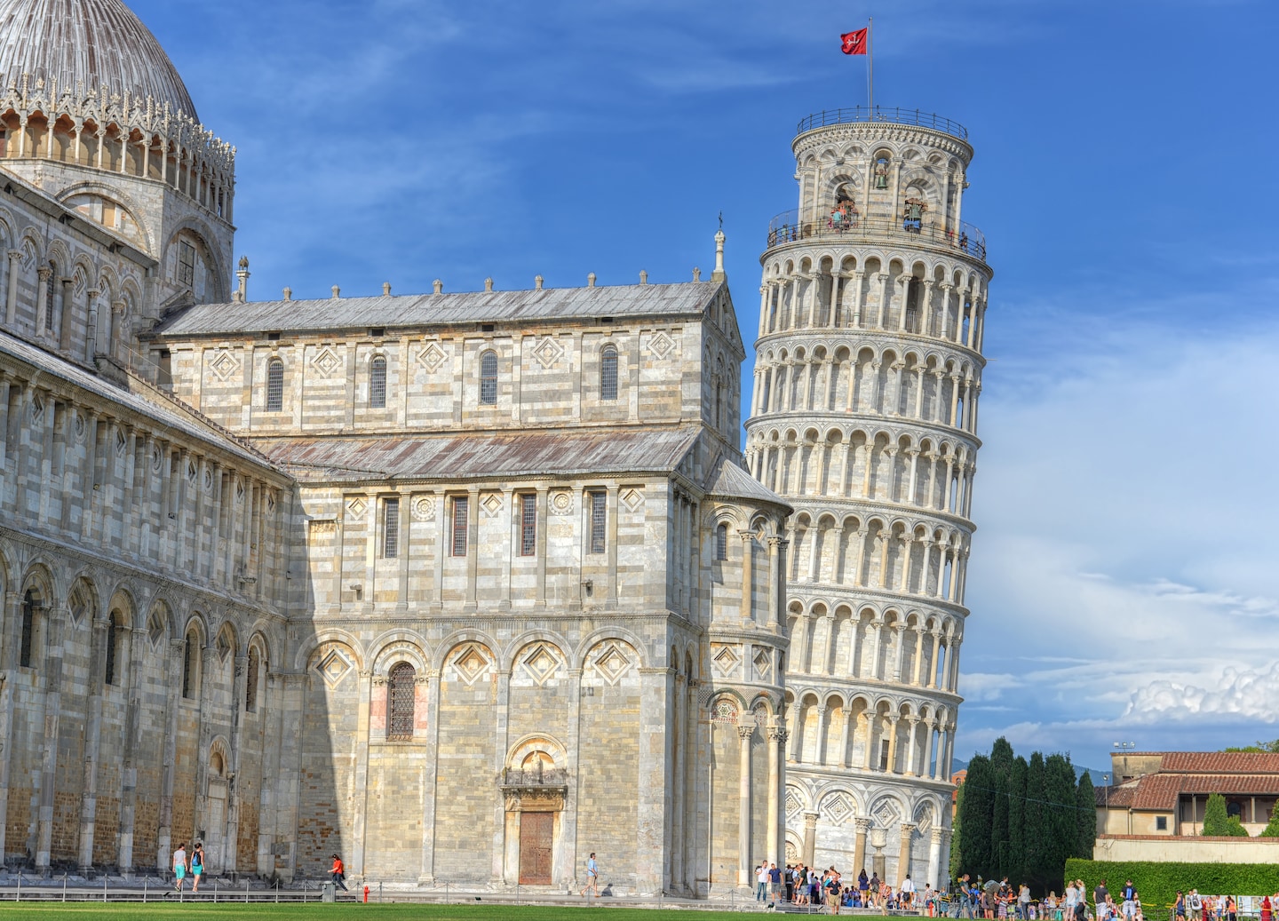 Sunlit Leaning Tower overlooks visitors exploring Pisa’s open grassy grounds. - Florence / Pisa (La Spezia), Italy