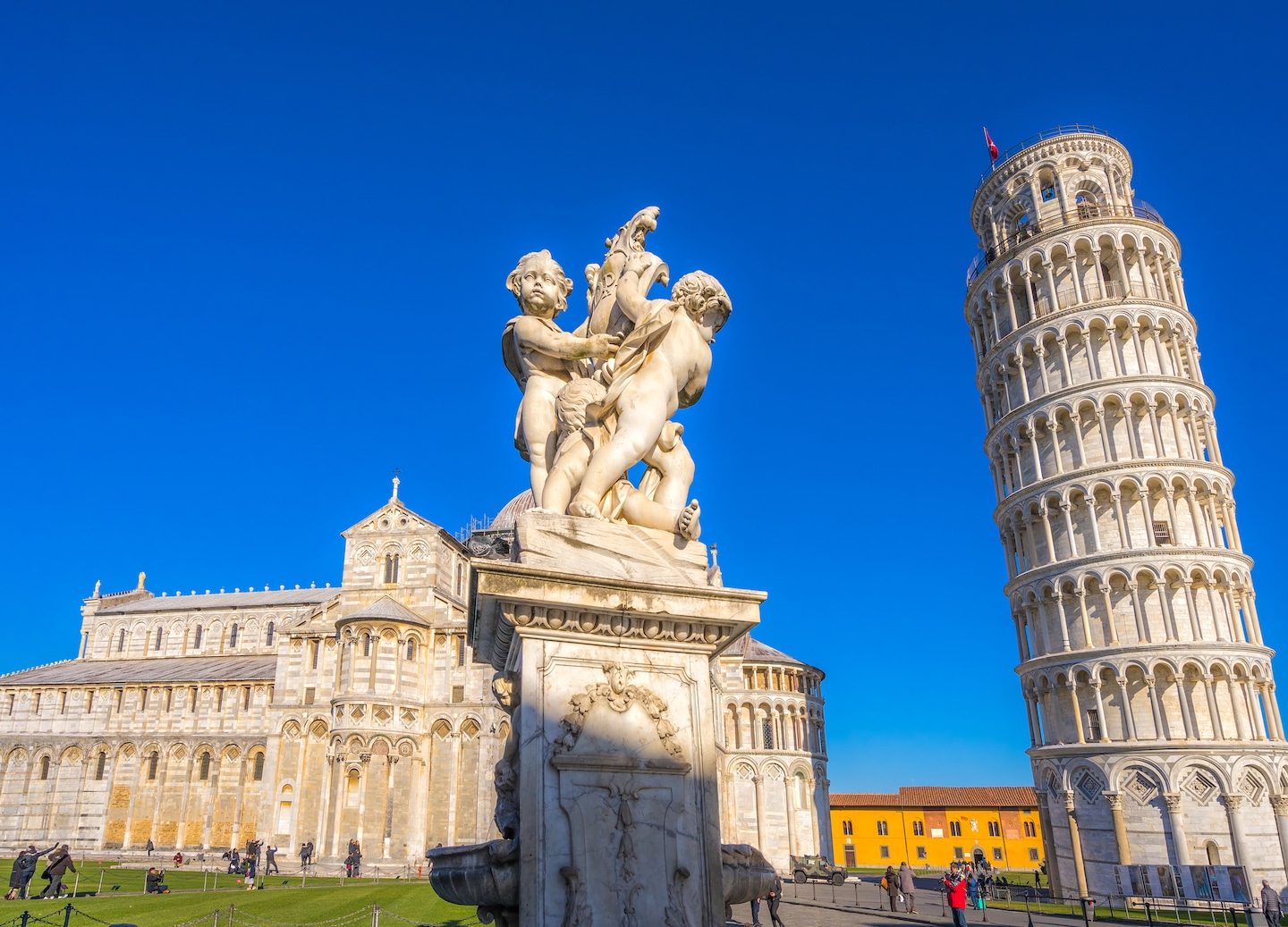 Leaning Tower stands tall over visitors under a blue sky. - Florence / Pisa (La Spezia), Italy