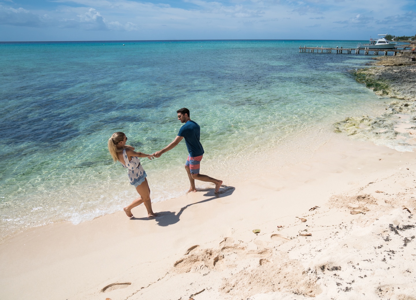 A couple playing in turquoise waves along Seven Mile Beach’s shoreline. - George Town, Grand Cayman