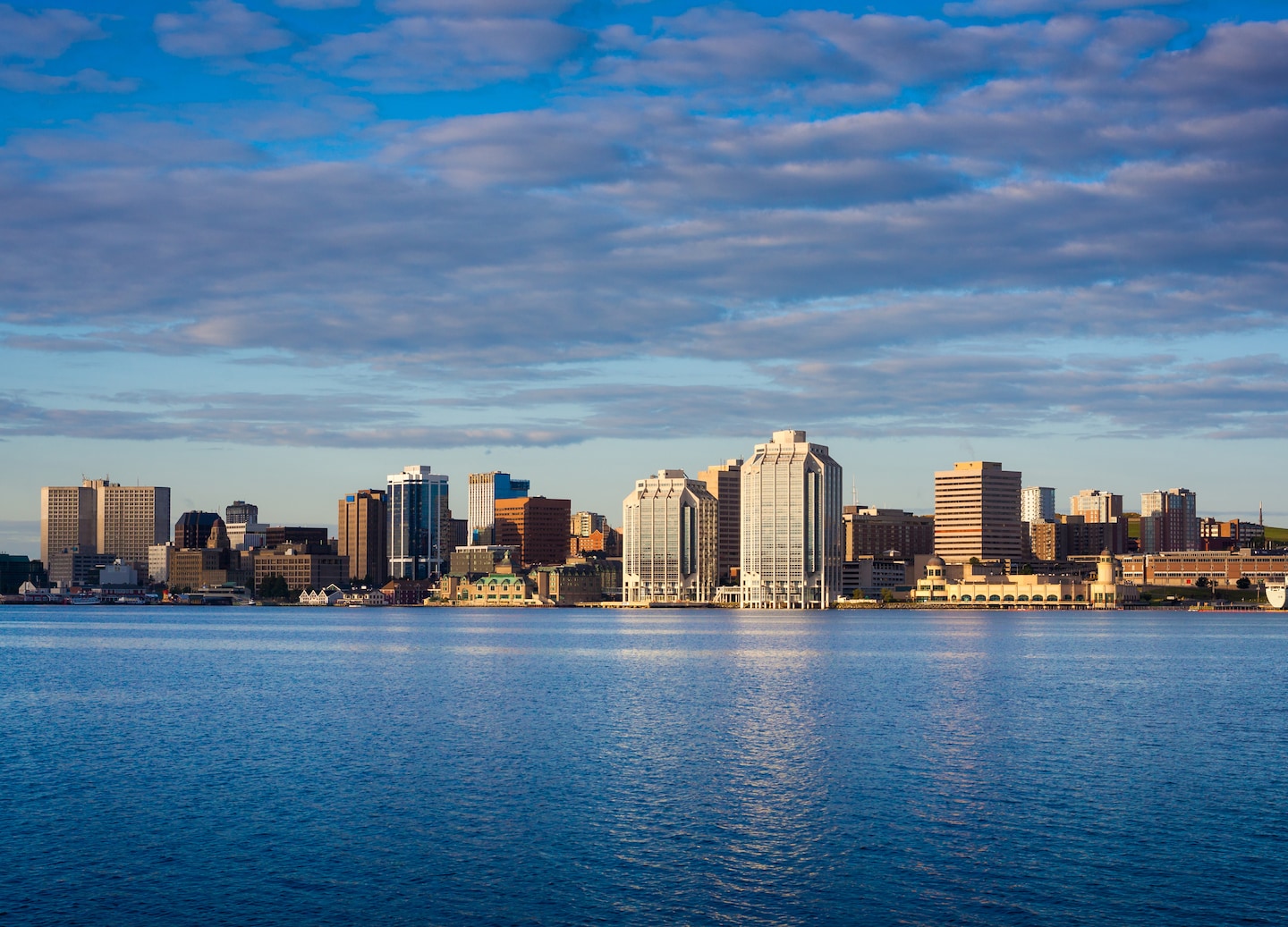Downtown Halifax rises above the waterfront, with Purdy’s Wharf reflecting across the calm harbor. - Halifax, Nova Scotia