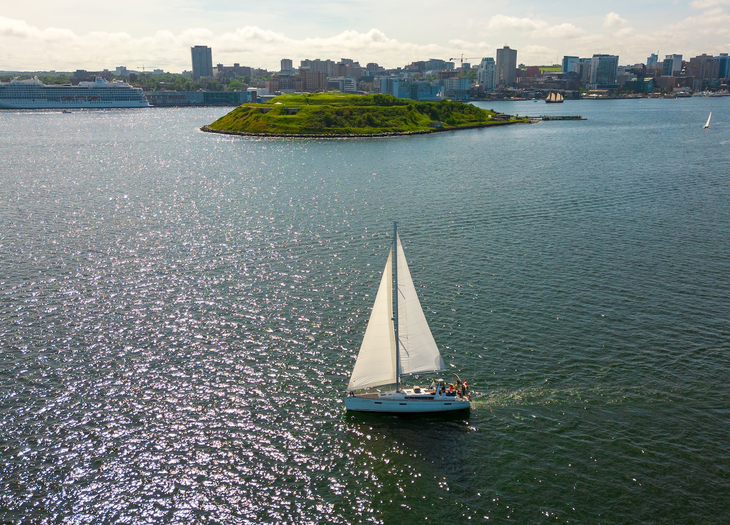 A sailboat passes Georges Island in Halifax Harbour, with its historic fort visible above the water. - Halifax, Nova Scotia