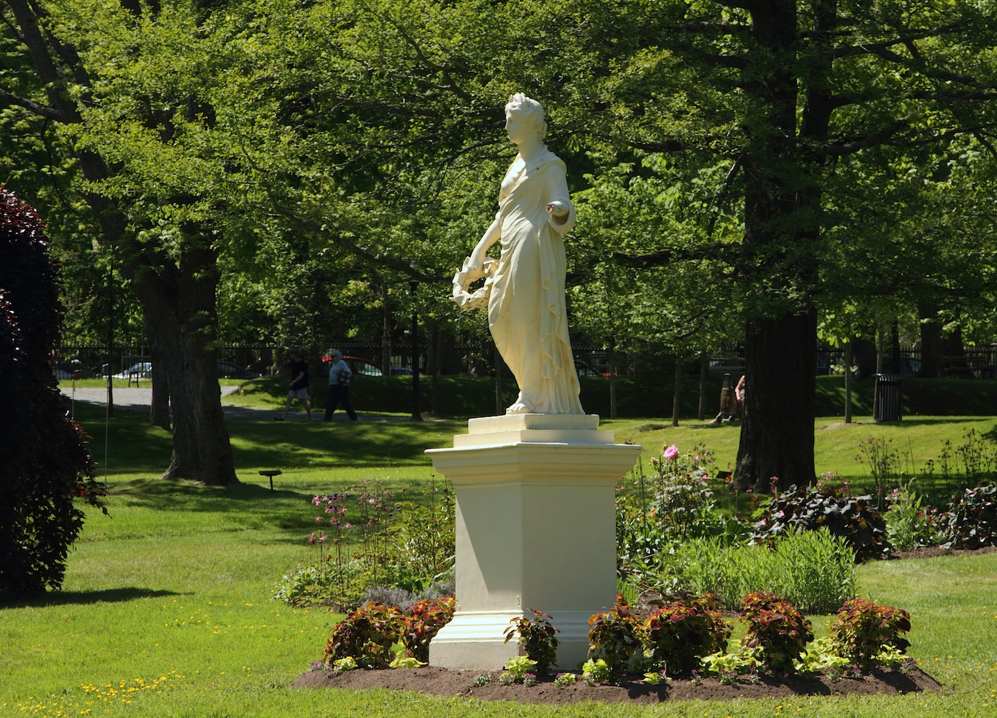 A statue stands among vibrant flowers and manicured greenery in Halifax’s peaceful Public Gardens. - Halifax, Nova Scotia