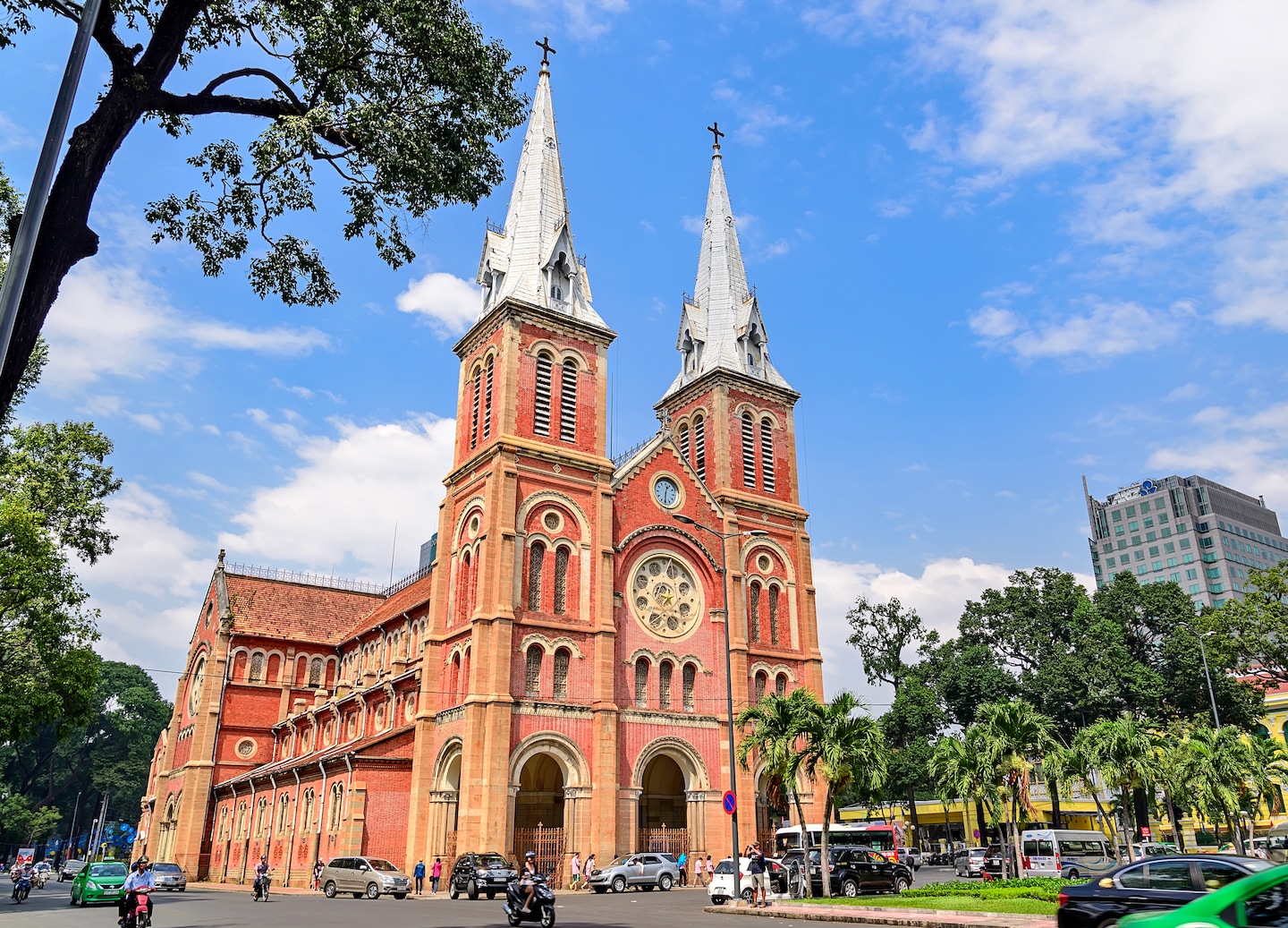 Red‑brick Notre Damn Cathedral of Saigon against bright blue sky.