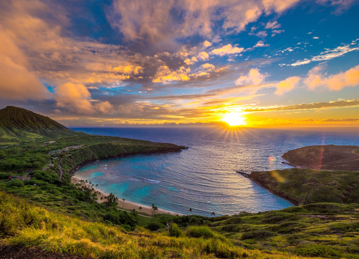 Sunrise light glows over Hanauma Bay, illuminating its curved cliffs and clear blue water. - Honolulu, Oahu, Hawaii