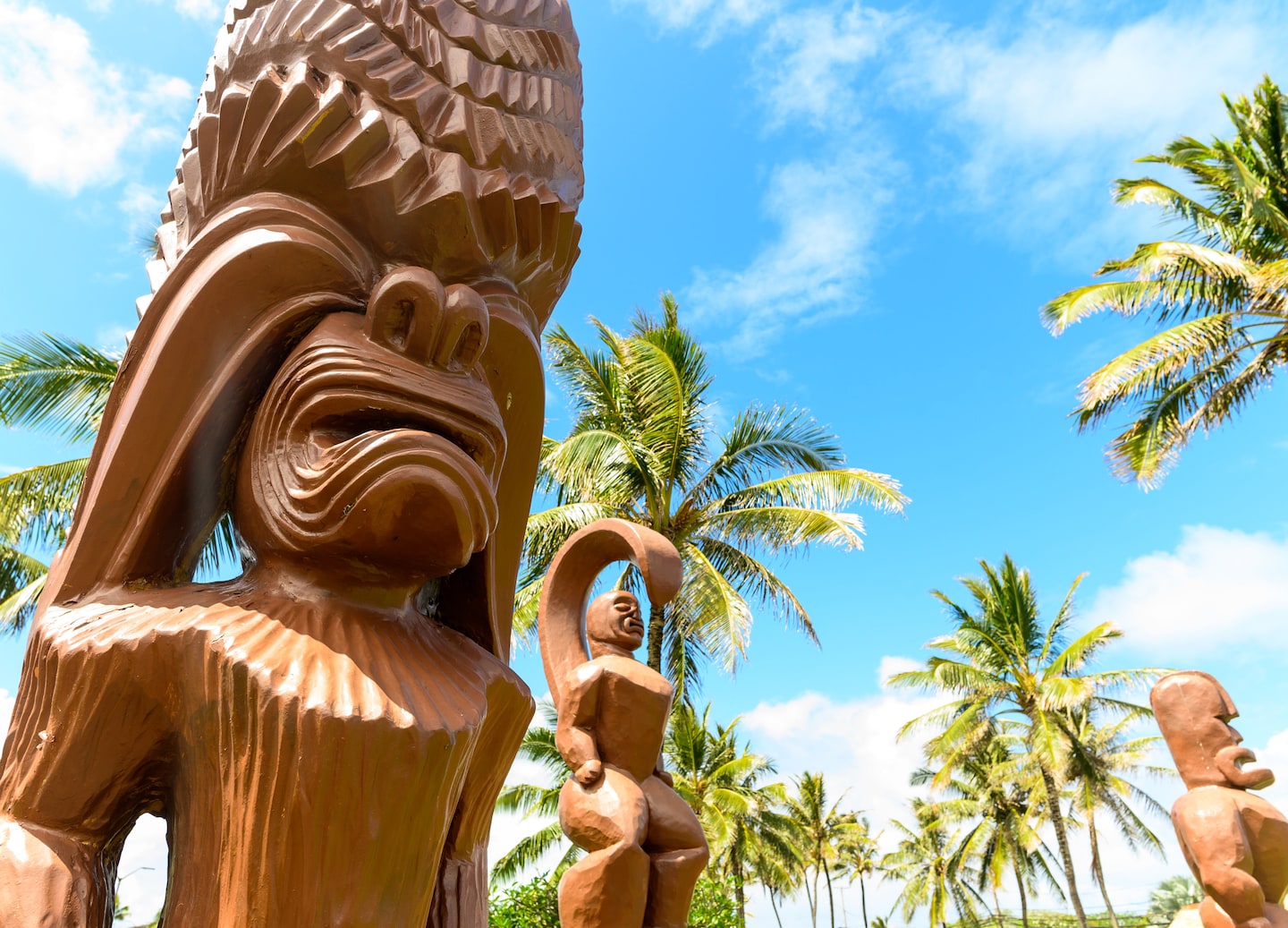 Carved Polynesian statues stand among tropical greenery at the Polynesian Cultural Center. - Honolulu, Oahu, Hawaii