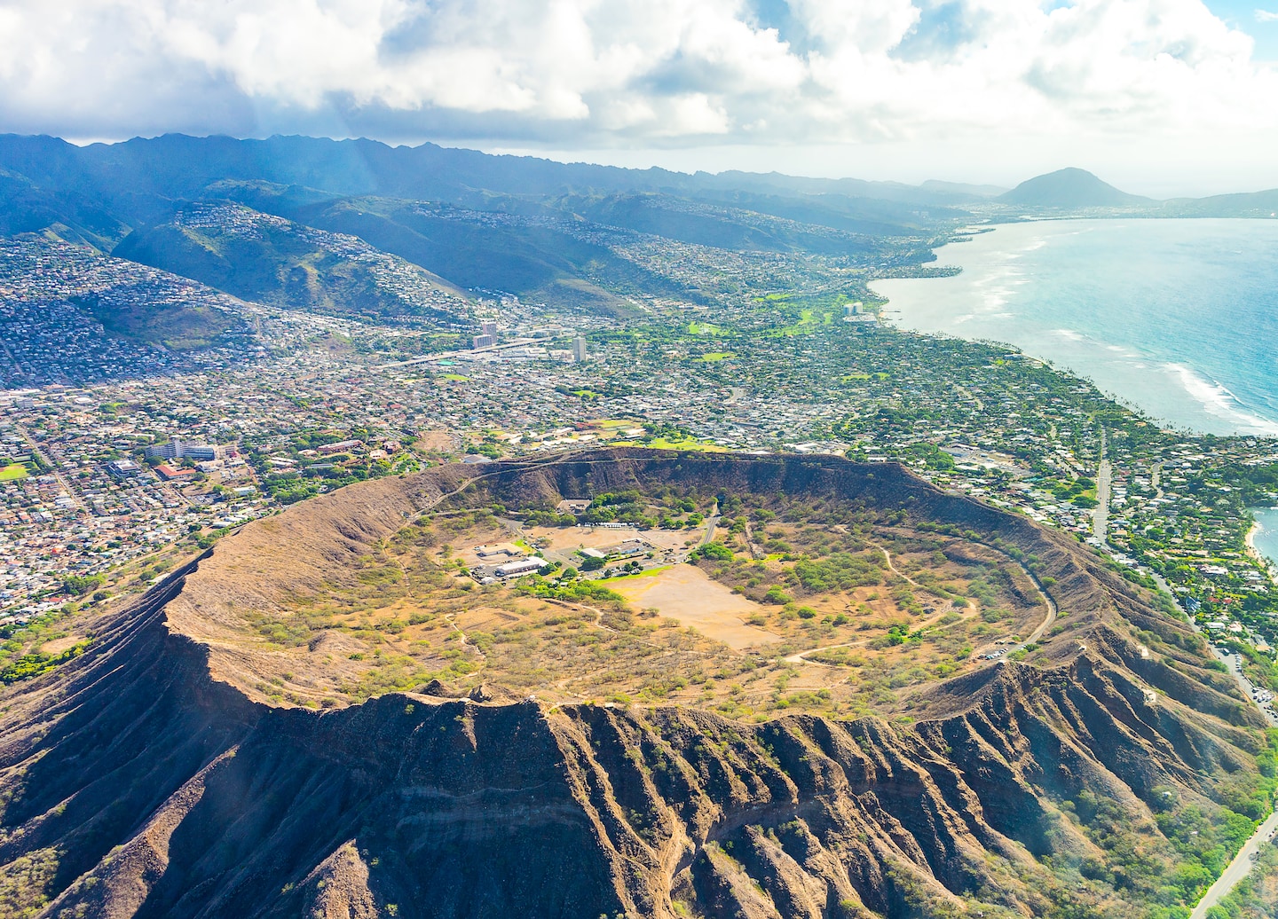 An aerial view shows Diamond Head rising above Honolulu’s coastline and the city’s beachfront skyline. - Honolulu, Hawaii