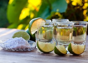 gold tequila with salt and lime on old wooden table