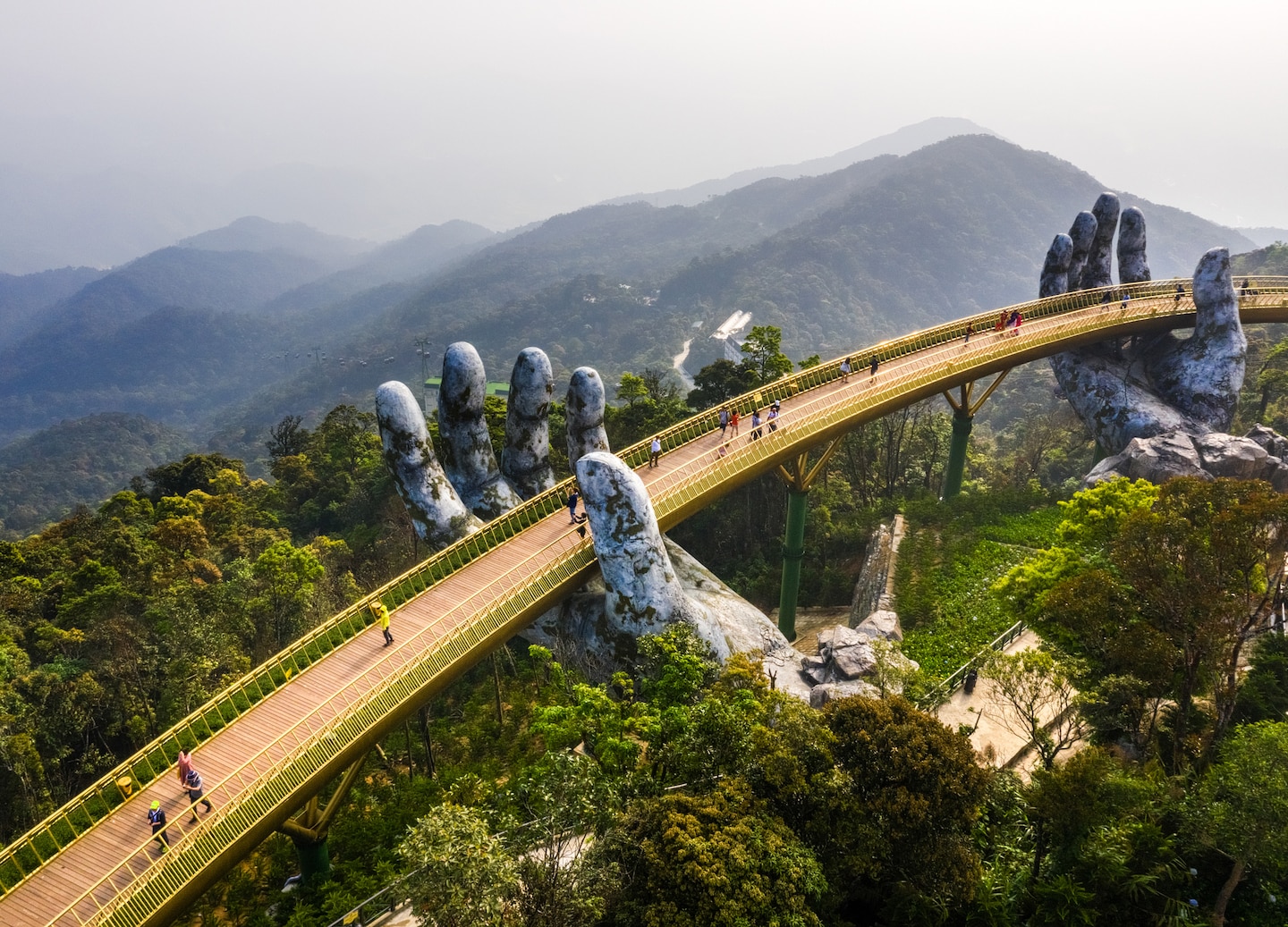 Golden Bridge curves above Ba Na Hills, supported by towering stone hands. - Da Nang City, Vietnam