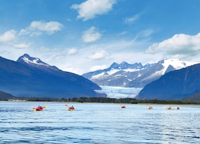 people paddle kayak in cold water near glacier in alaska
