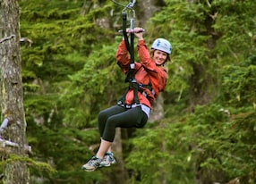 woman holding onto alpine zipline zip line going over forest
