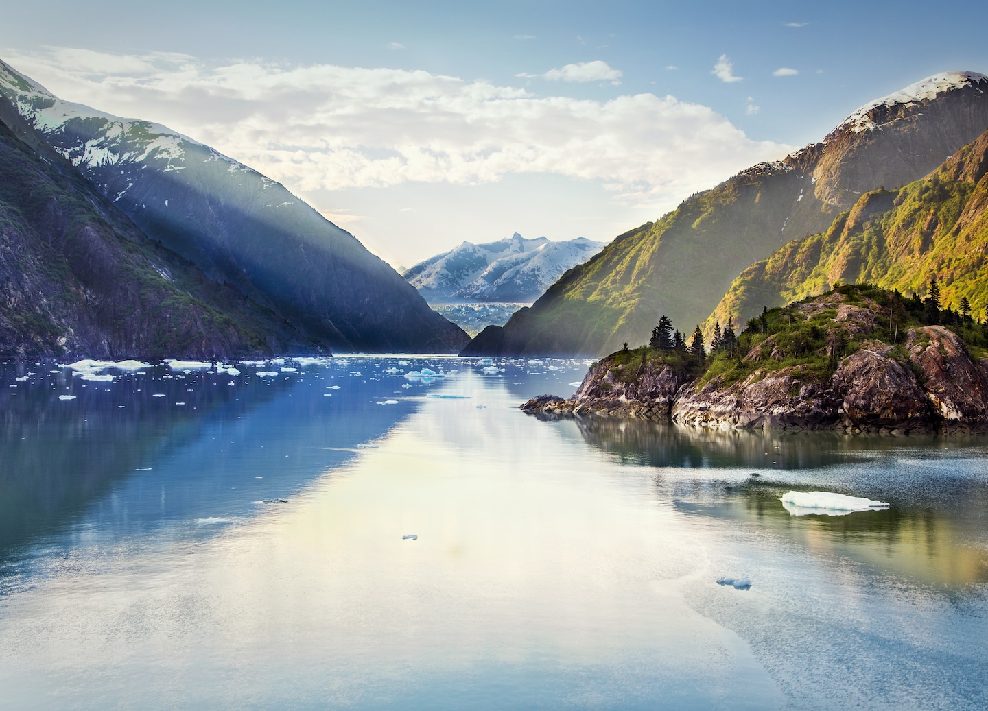 Steep granite walls rise above icy Tracy Arm waters under sunlight. - Juneau, Alaska