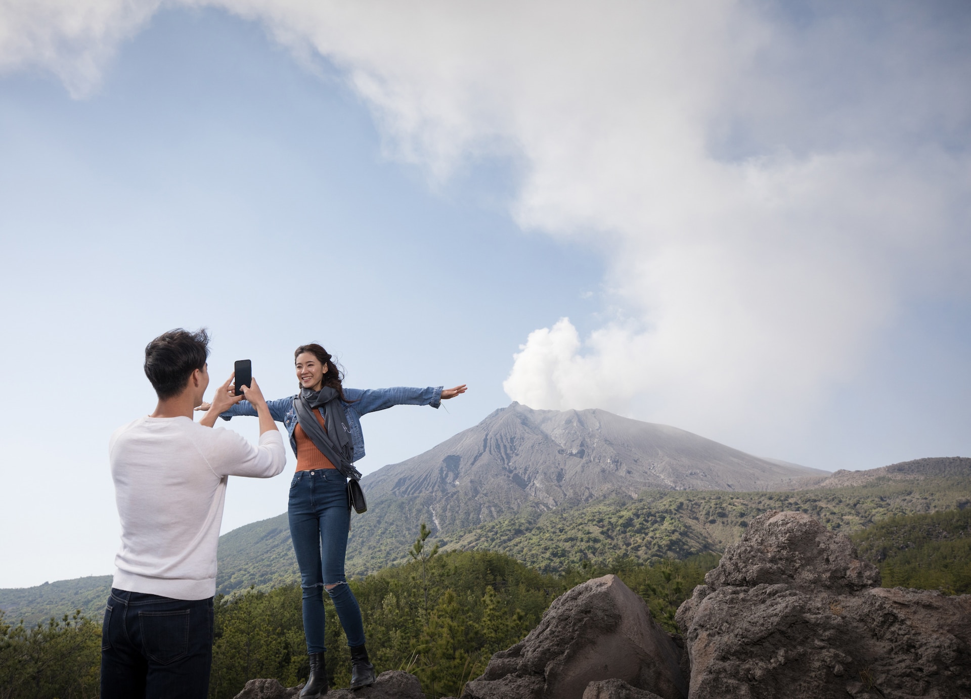 couple taking pictures infront of sakurajima volcano observatory