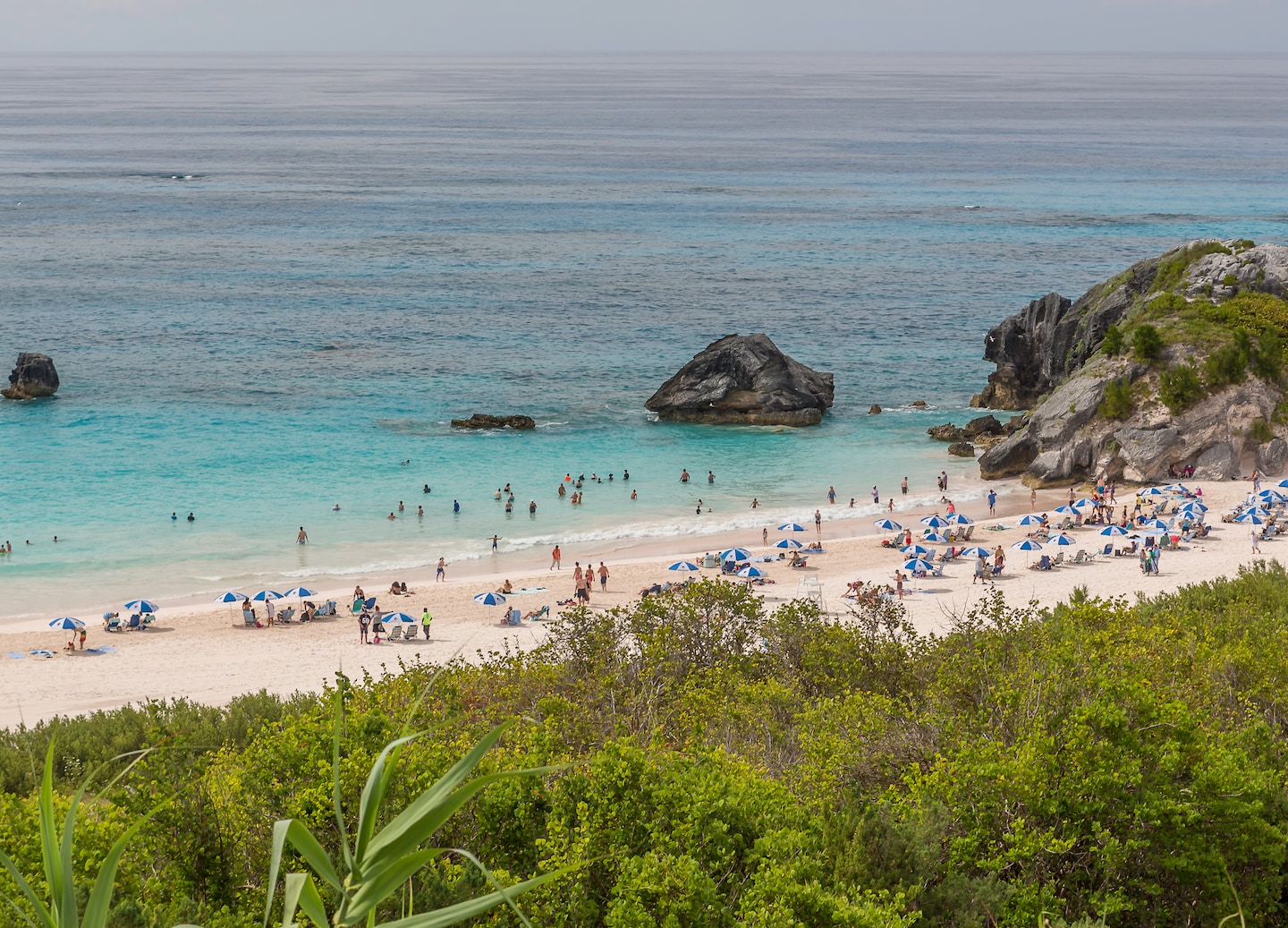 Rocky shoreline and sandy beach overlook turquoise ocean waters under clear skies. - Royal Naval Dockyard, Bermuda