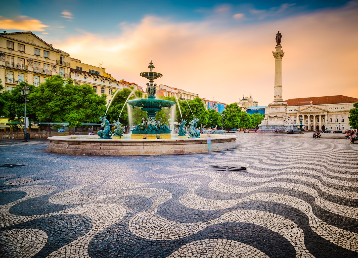 Rossio Square’s patterned plaza opens toward historic Lisbon buildings under bright afternoon light. - Lisbon, Portugal