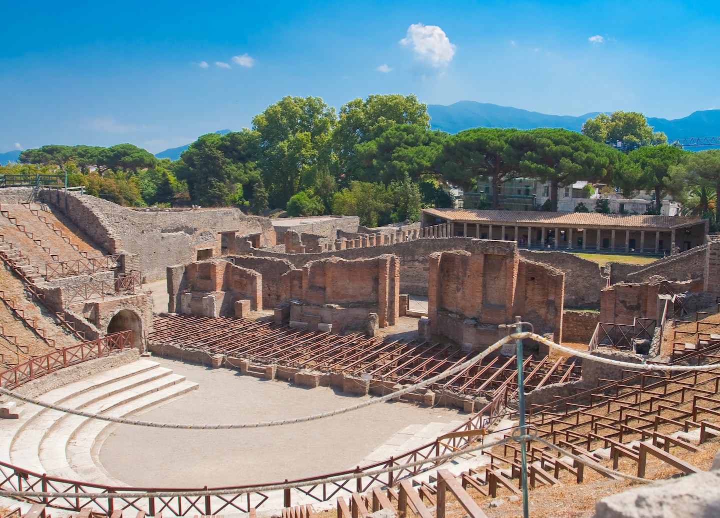Ancient Pompeii ruins stretch across sunlit landscape beneath clear blue sky. - Naples, Italy
