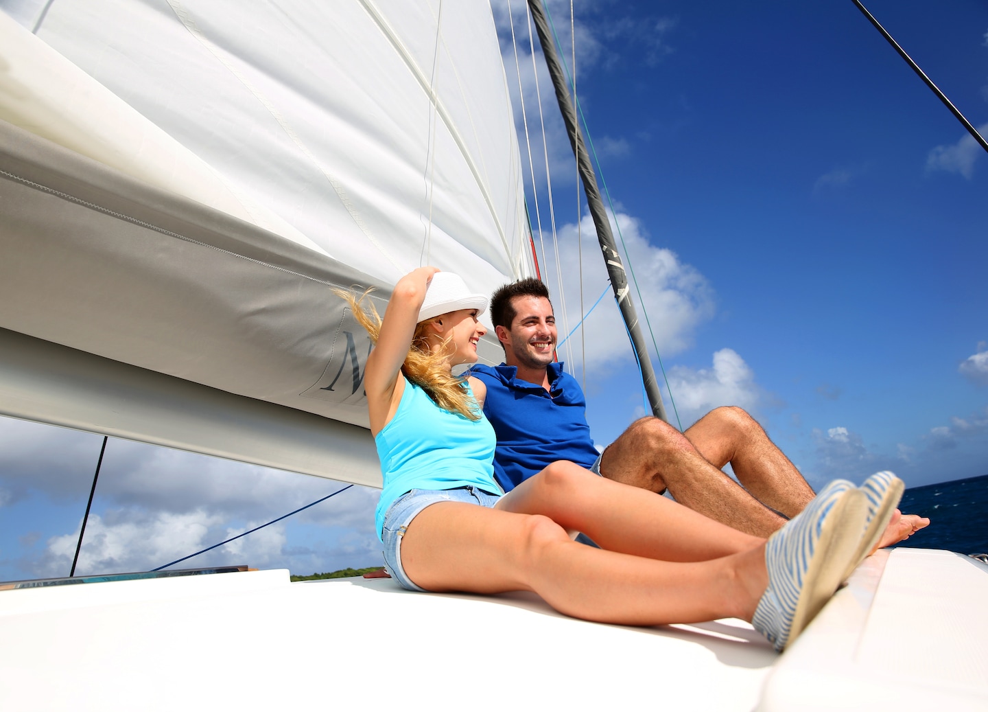 A couple relaxes on a sailboat deck. - Bahamas