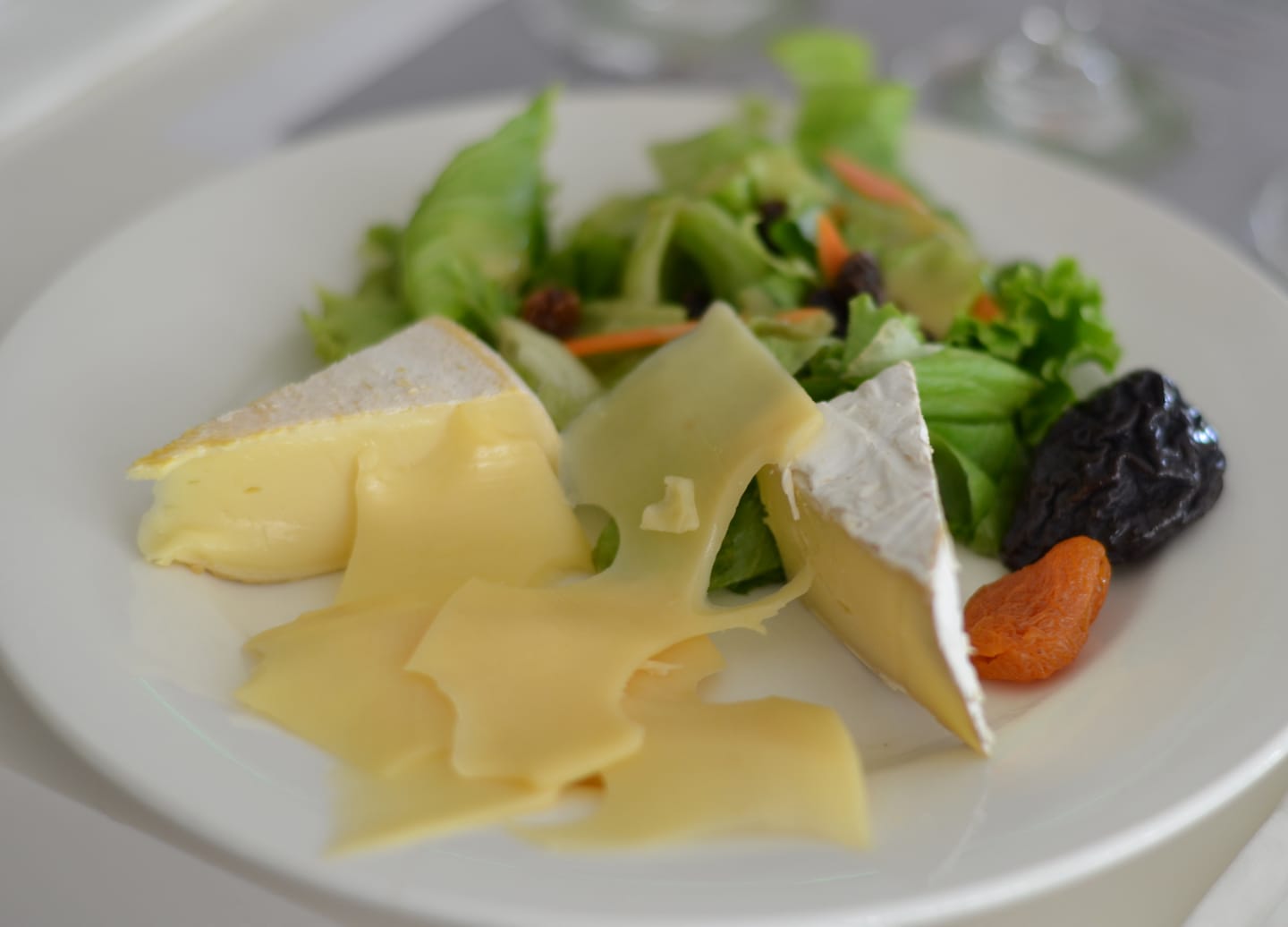 A wooden board holds assorted cheeses, nuts, fruit, and crackers arranged for a tasting. - Noumea, New Caledonia