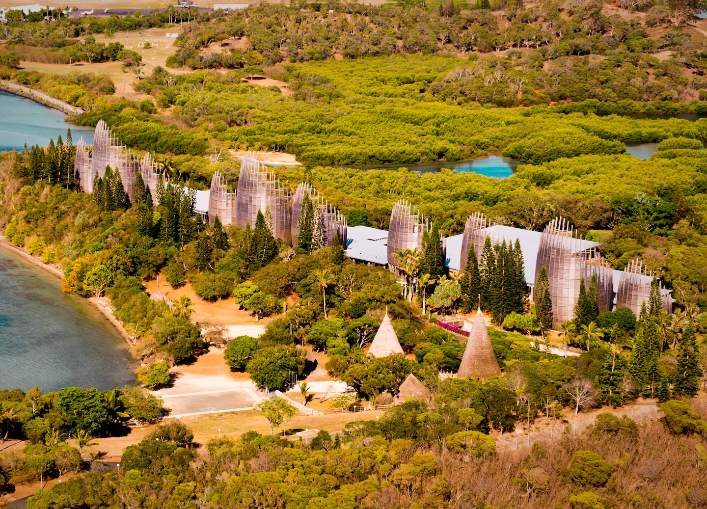 The Tjibaou Cultural Center’s tall, curved wooden pavilions rise above lush greenery in an aerial view. - Noumea, New Caledonia