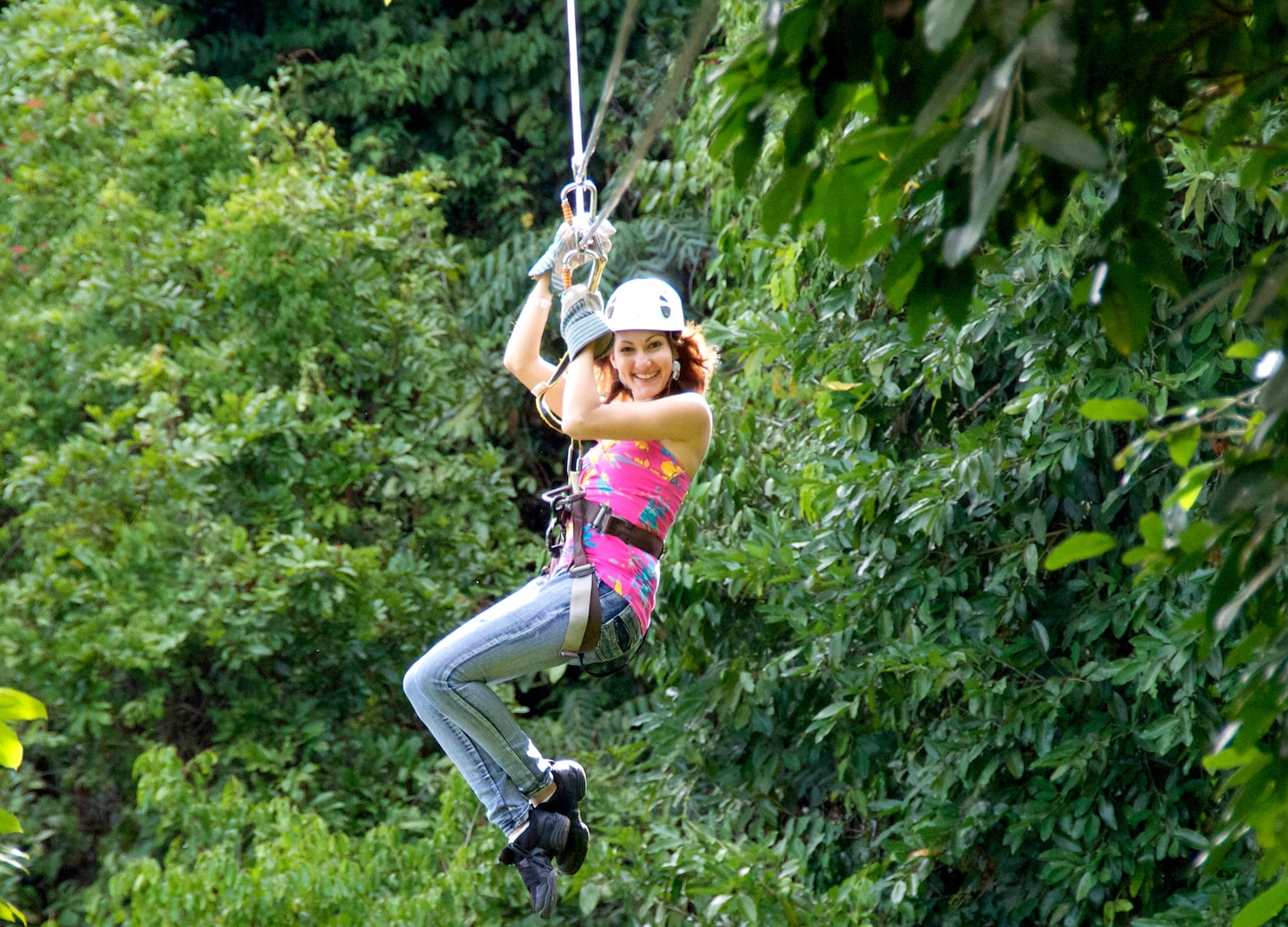 A guest glides along a zipline through lush forest canopy. - Ocho Rios, Jamaica