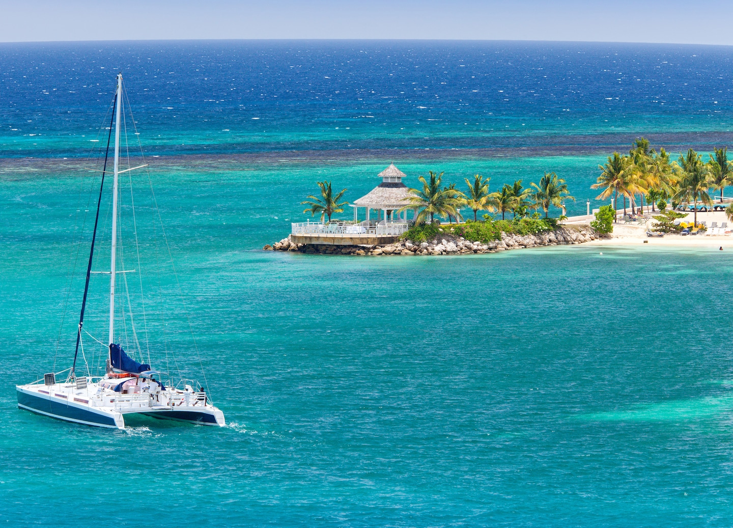 Catamaran sails across turquoise Caribbean waters. - Ocho Rios, Jamaica