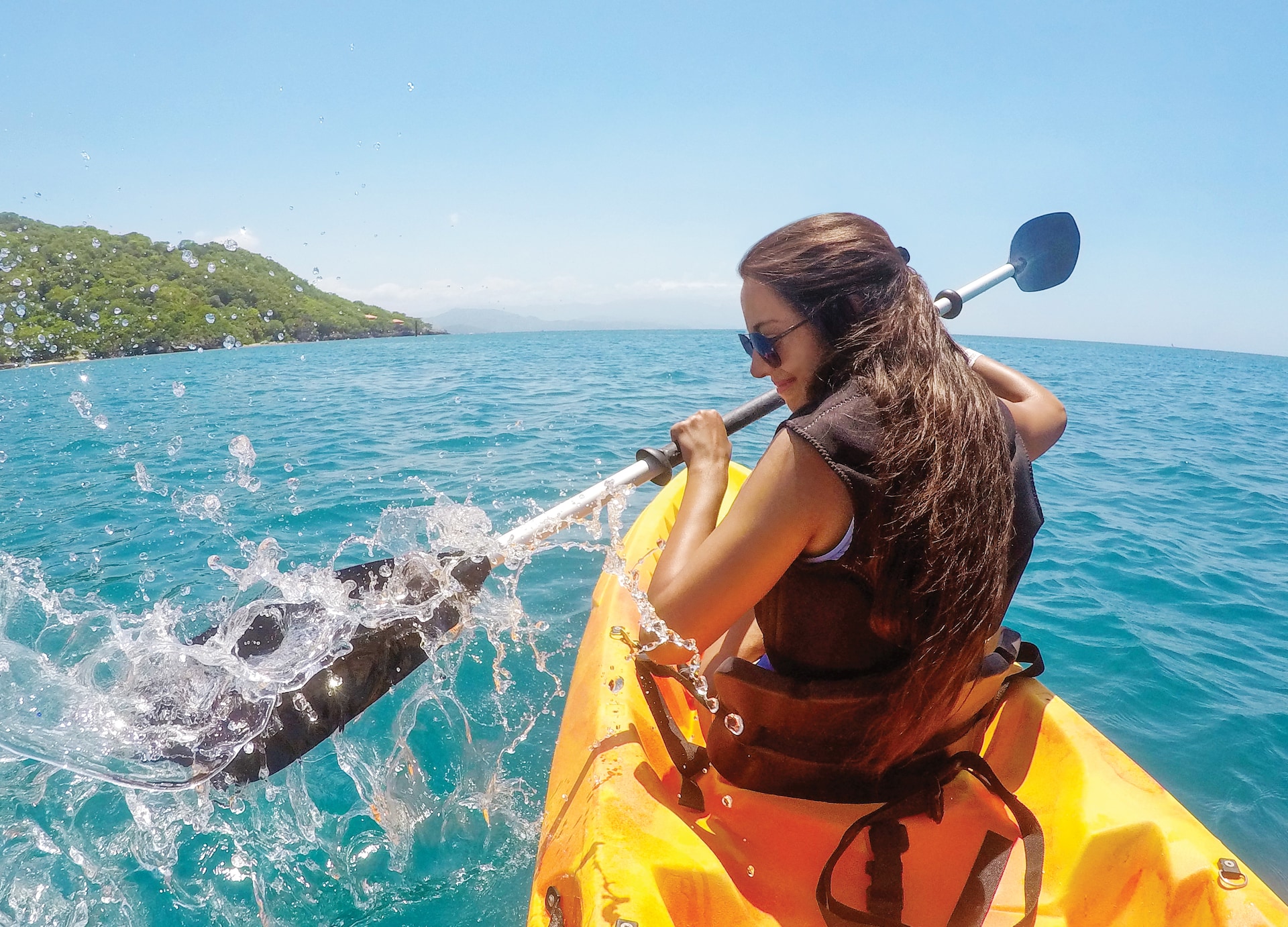 girl paddle in kayak clear water with island in background