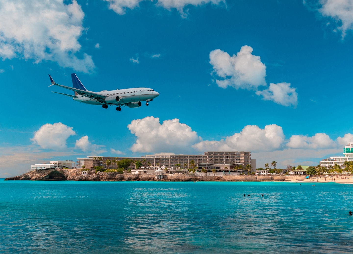 Airplane descends low over Maho Beach as visitors watch from the shoreline. - Philipsburg, St. Maarten