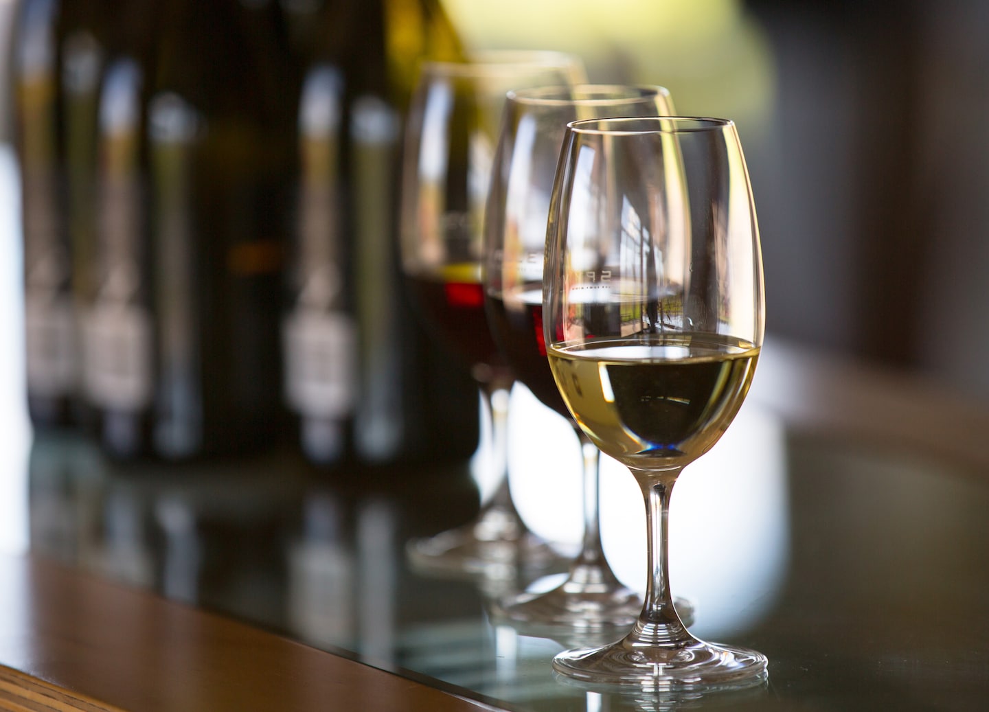 Assorted wine bottles and filled glasses arranged on tasting table. - New Zealand