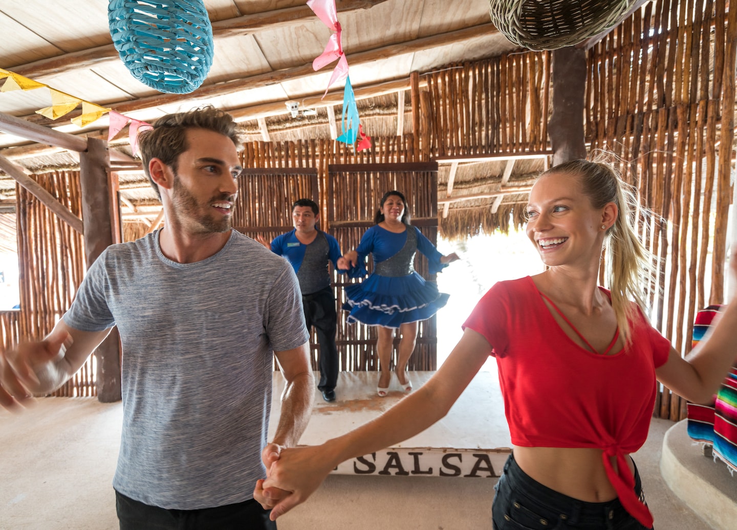 A couple practices salsa steps together, smiling as they dance during a lesson. - Puerto Costa Maya, Mexico 