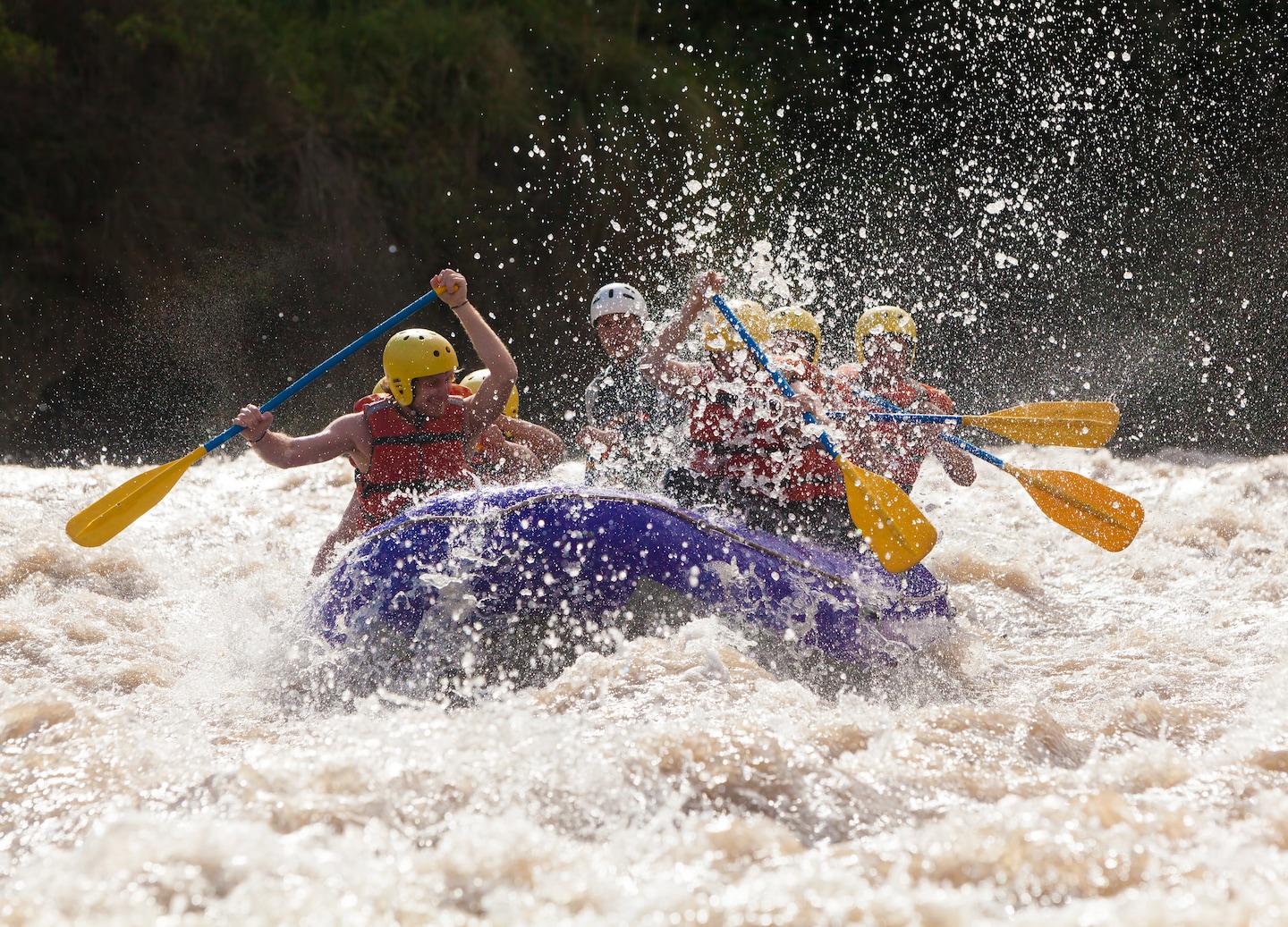 A group paddles through fast whitewater rapids as their rafting guide steers the boat downstream. - Puerto Limón, Costa Rica