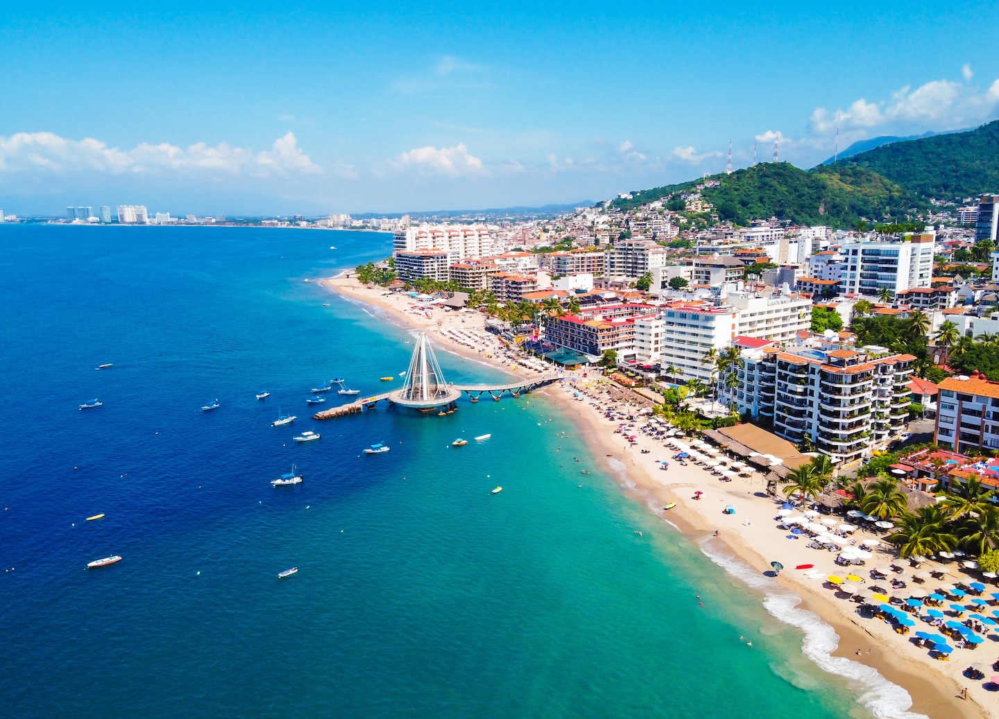 An aerial view of Puerto Vallarta reveals its curved coastline, blue bay, and vibrant cityscape. - Puerto Vallarta, Mexico