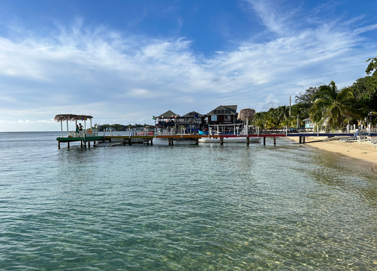 West End Village’s waterfront shows colorful buildings, boats, and calm Caribbean water along Roatán’s coast. - Roatan, Honduras