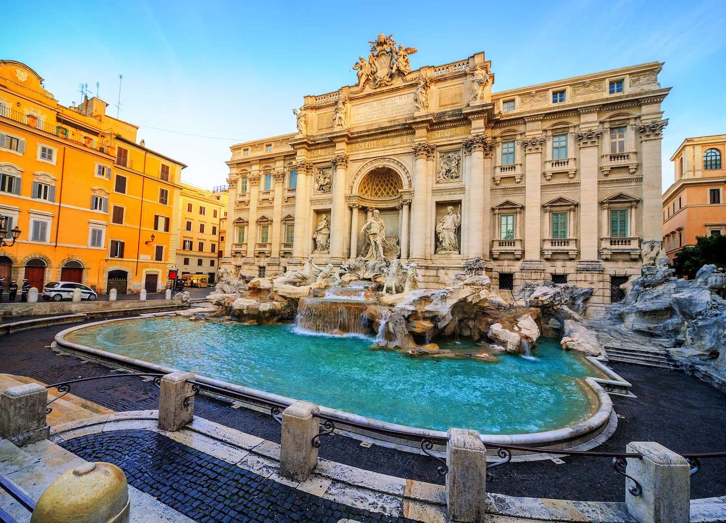 Morning light brightens the Trevi Fountain, its carved figures rising above shimmering turquoise water. - Rome, Italy
