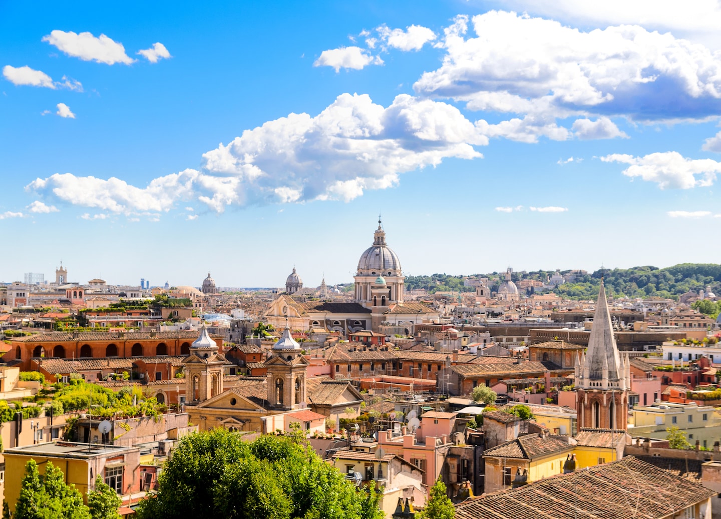 A panoramic view of Rome stretches toward St. Peter’s Basilica beneath a warm, hazy sky. - Rome, Italy