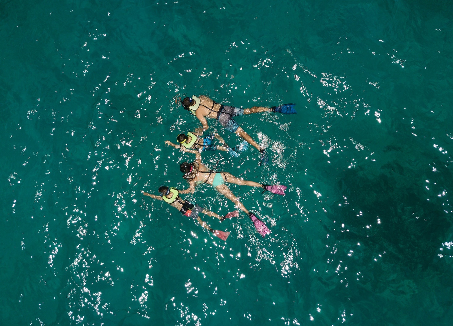 A family snorkels together in clear Caribbean water above bright fish and shallow reef. - San Juan, Puerto Rico