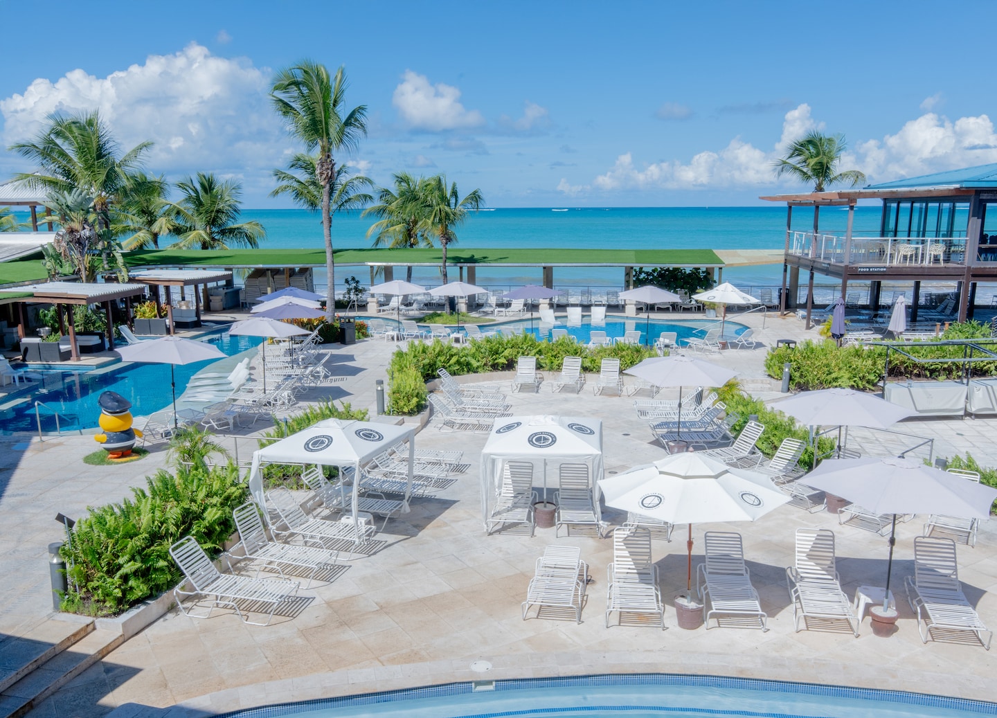 An aerial view shows Vivo Beach Club’s white sand, turquoise water, and palm‑lined shoreline. - San Juan, Puerto Rico