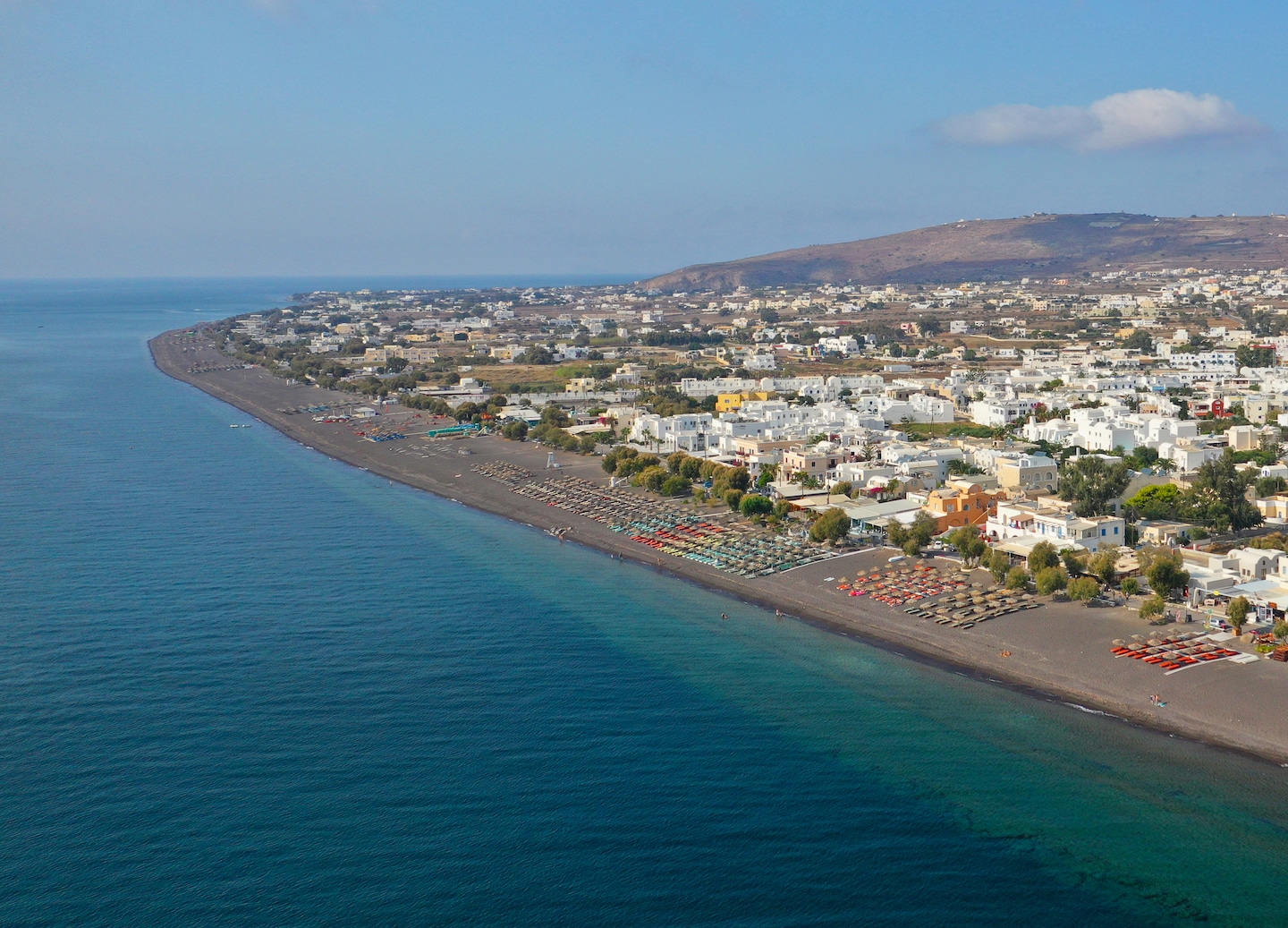 Relax at Perivolos Beach with black sand, calm waters, and chic seaside lounges. - Santorini, Greece