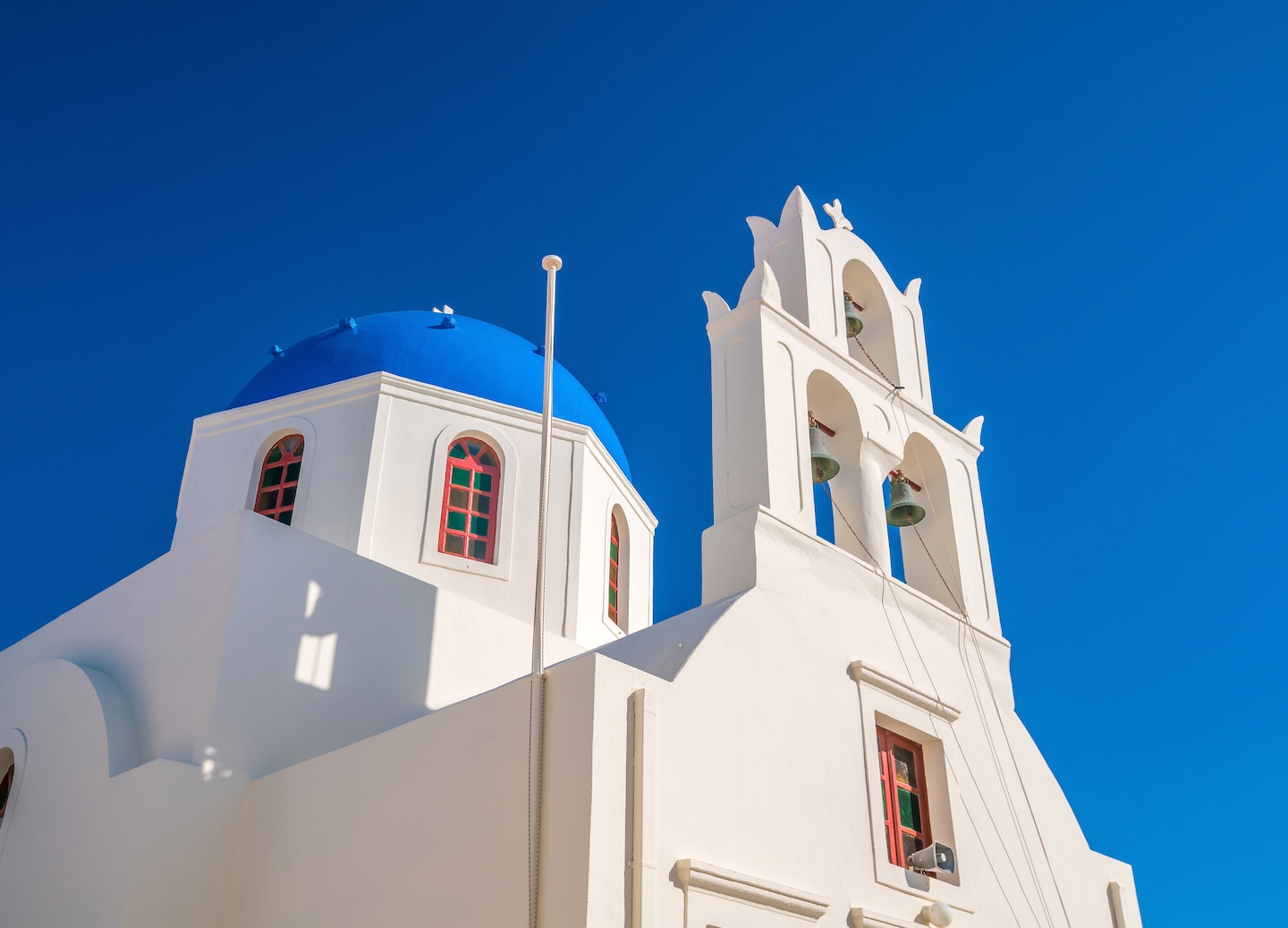 View of the Three Bells of Fira, a blue-domed Catholic church with three arched bells. - Fira, Santorini