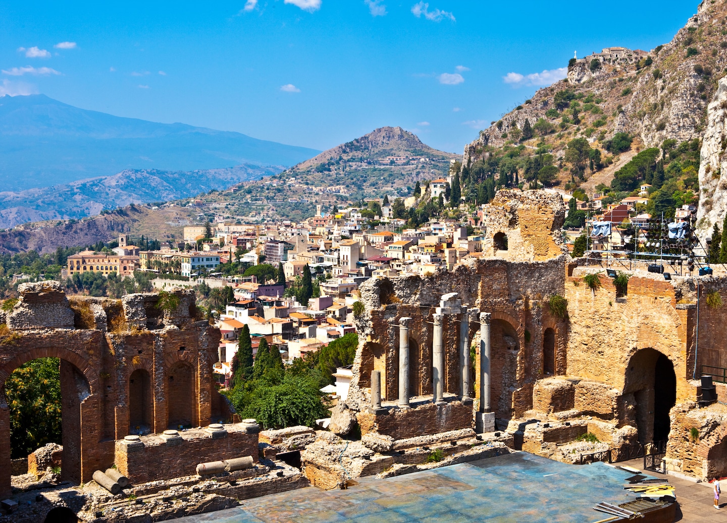 Hillside buildings overlook the coastline with Mount Etna rising in the background. - Sicily, Italy