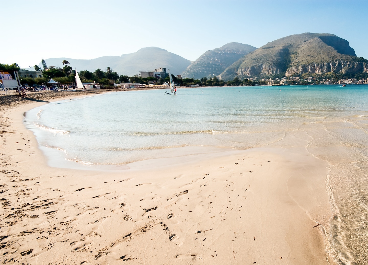Mondello Beach’s bright turquoise water meets soft white sand beneath a clear Sicilian summer sky. - Palermo, Italy