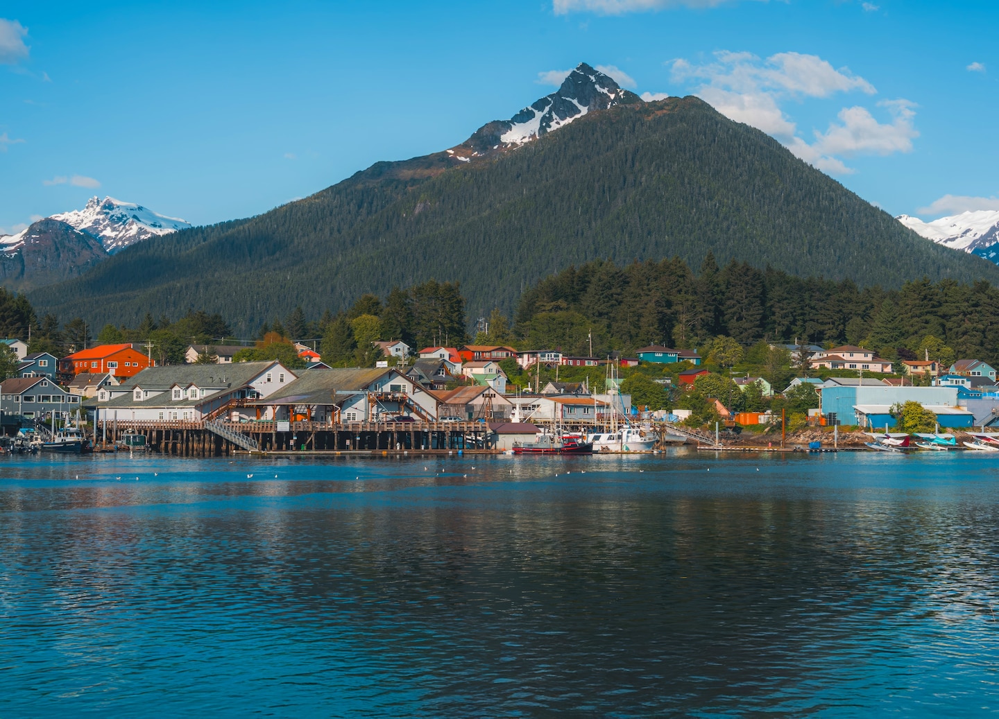 Sitka’s harbor sits beneath misty mountains as boats line the quiet waterfront. - Sitka, Alaska