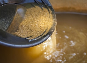 close up of gold panning pan with sifting sand shallow depth of field with focus on sand flowing