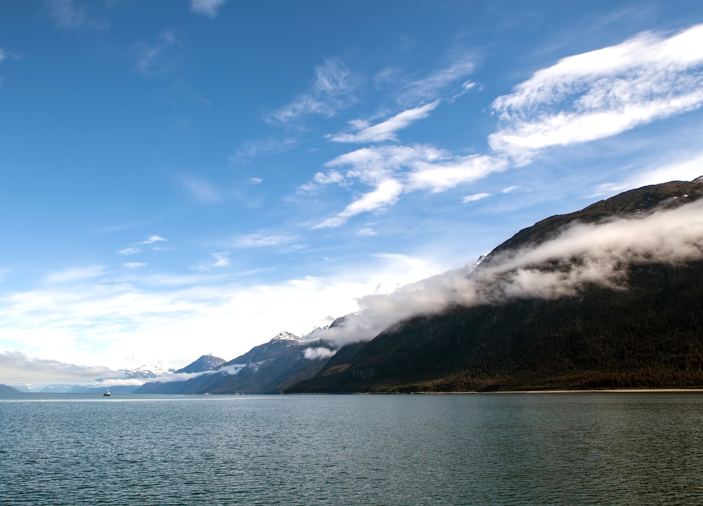 Calm Lynn Canal waters reflect misty mountains rising along Alaska’s rugged coast. - Haines, Alaska