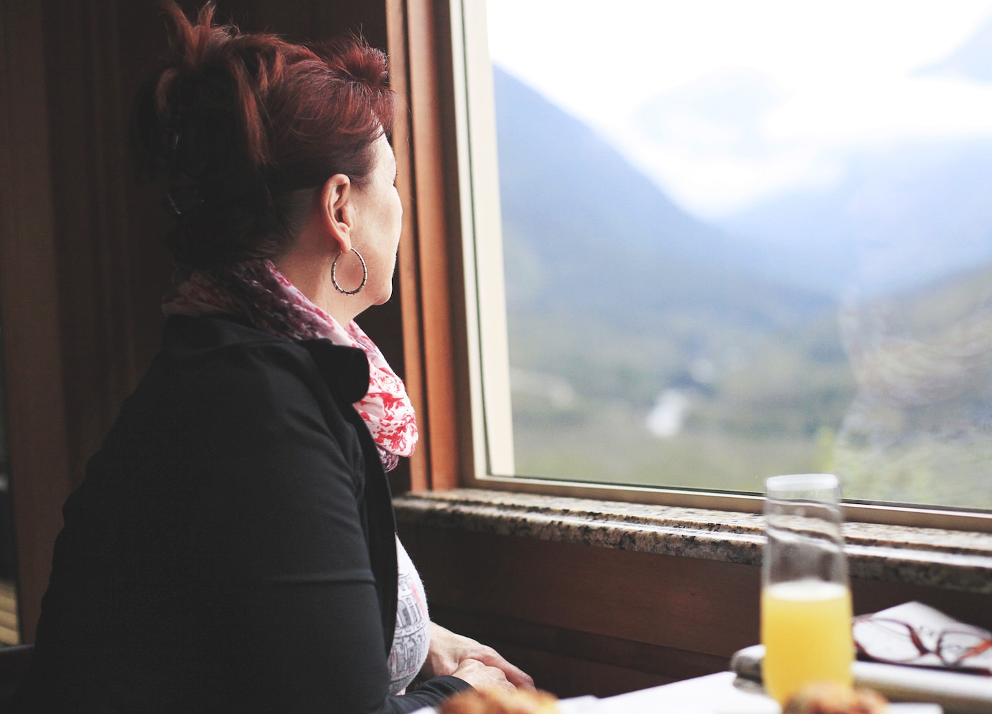 Passenger gazes from White Pass train as vast Alaskan mountains unfold outside. - Skagway, Alaska
