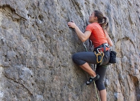 a young woman with a rope engaged in the sports of rock climbing on the rock