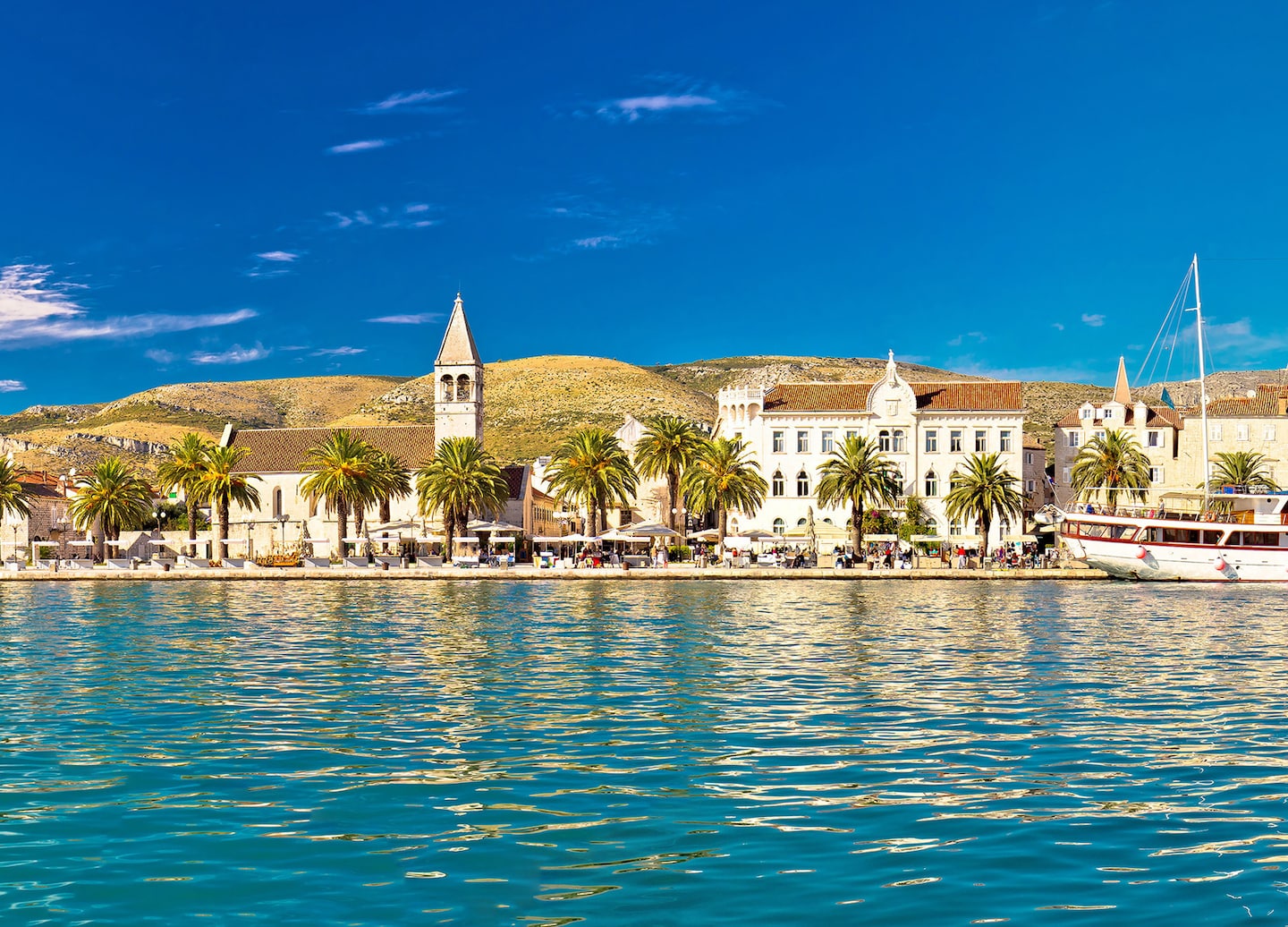 Trogir’s waterfront showcases stone buildings rising beside calm blue water. - Split, Croatia
