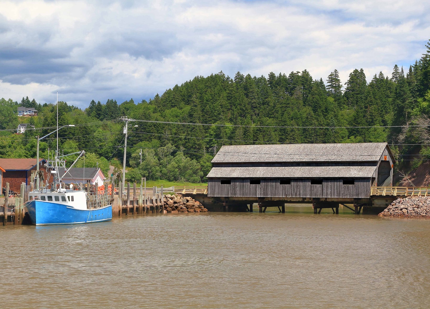 A wooden covered bridge in St. Martins spans a quiet creek surrounded by lush greenery. - Saint John (Bay of Fundy), New Brunswick