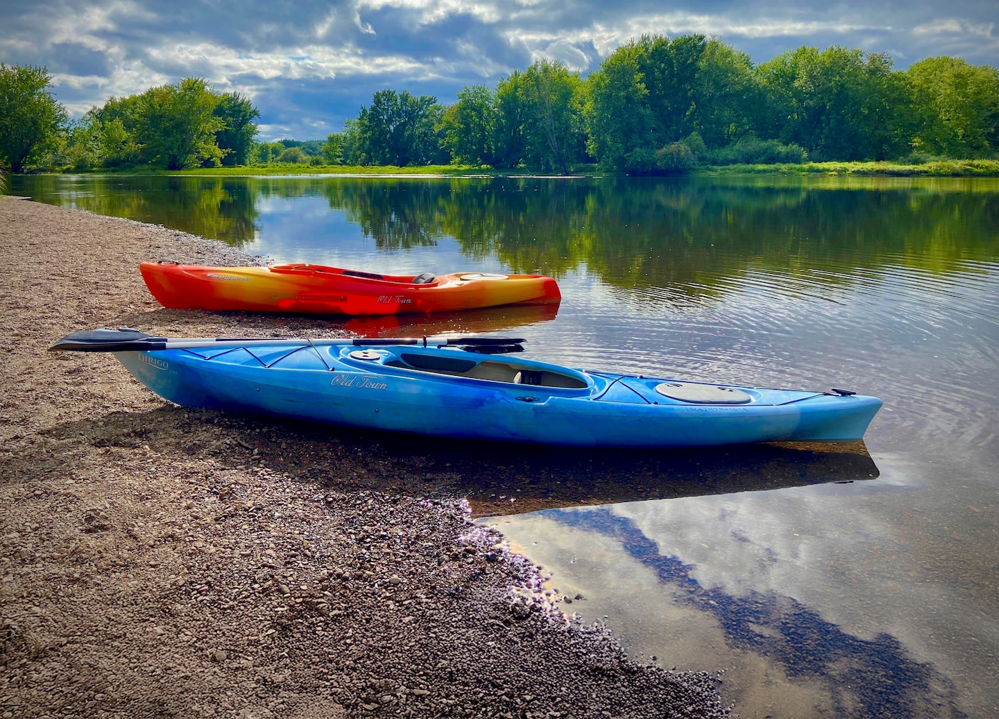Two kayaks rest on the calm Kennebecasis River, surrounded by trees and gentle shoreline. - Saint John (Bay of Fundy), New Brunswick