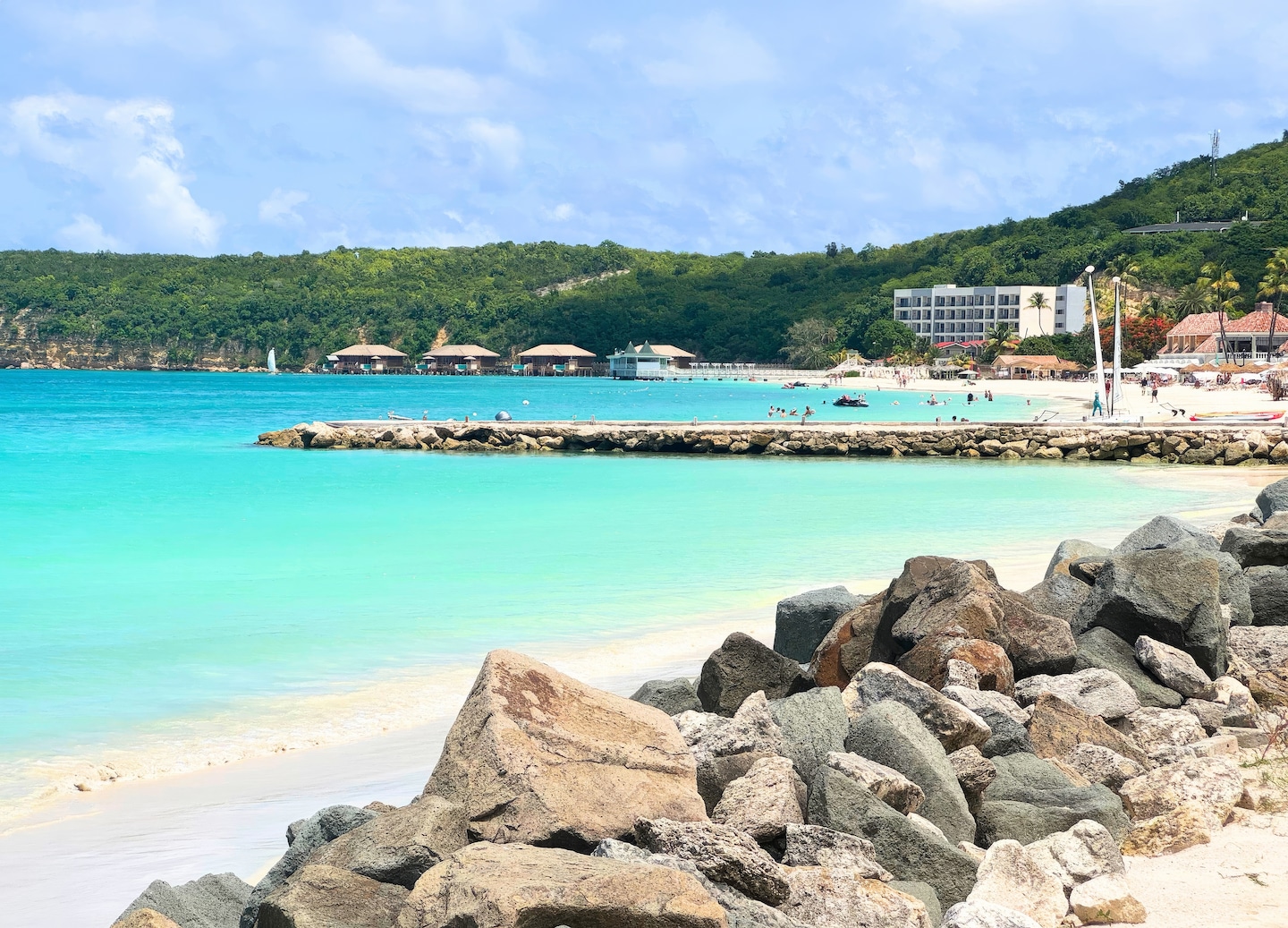 A rocky shoreline meets clear blue water as waves wash over stones on an Antigua beach. - St. Johns, Antigua